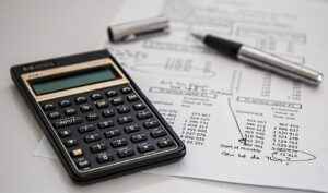 a calculator and open pen on top of business accounting paperwork