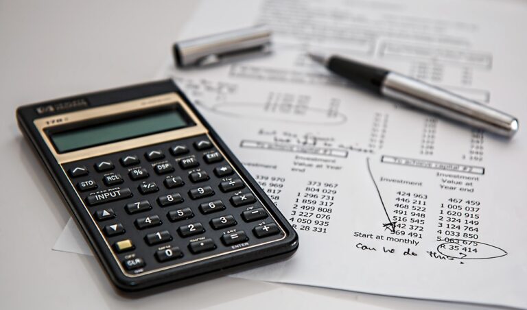 a calculator and open pen on top of business accounting paperwork