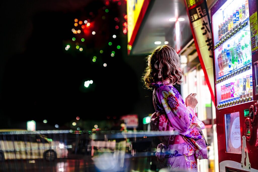 Woman buying from a vending machine at night.