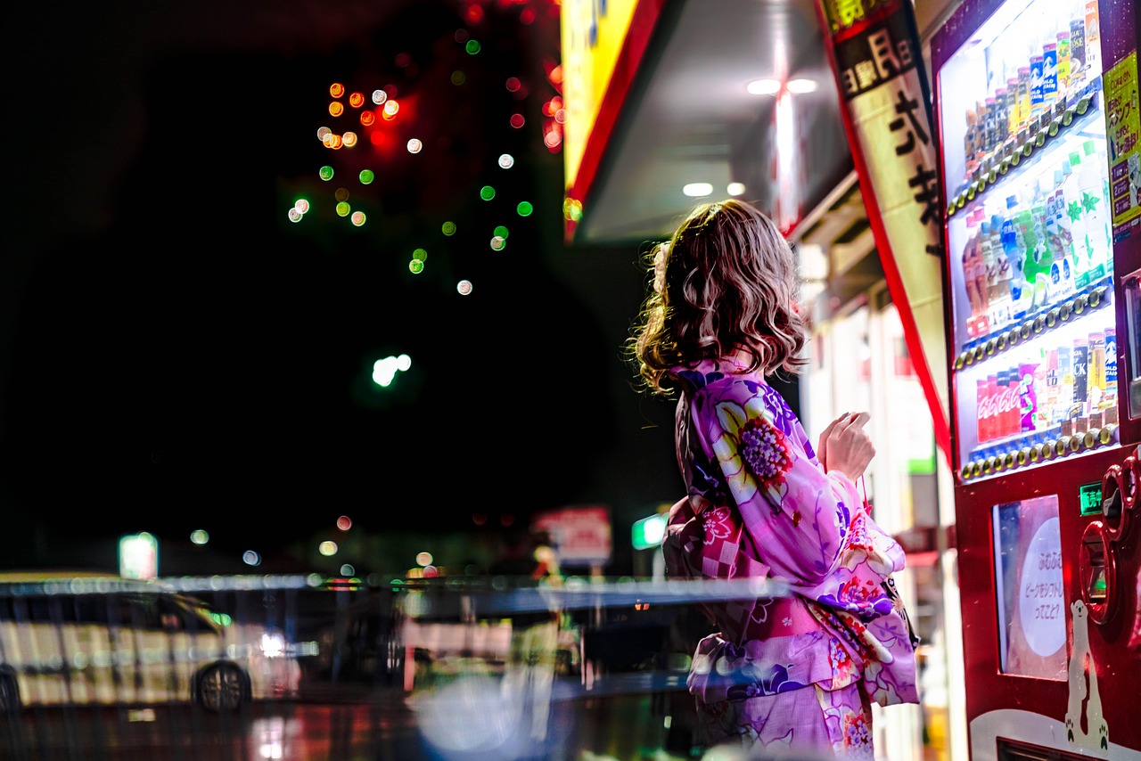Woman buying from a vending machine at night.
