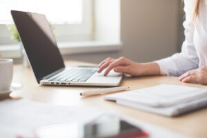 business woman with a laptop and notebook, presumably reviewing her post-acquisition integration plan
