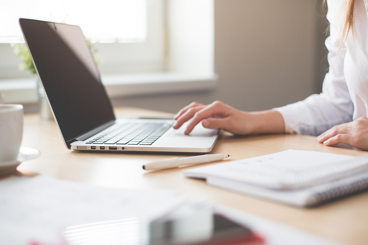 business woman with a laptop and notebook, presumably reviewing her post-acquisition integration plan