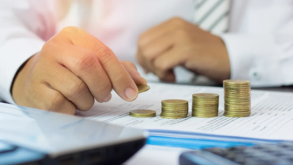 Businessperson stacking coins on financial reports, estimating net working capital