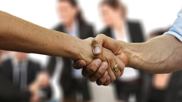 Close-up of a business handshake with colleagues out of focus in the background