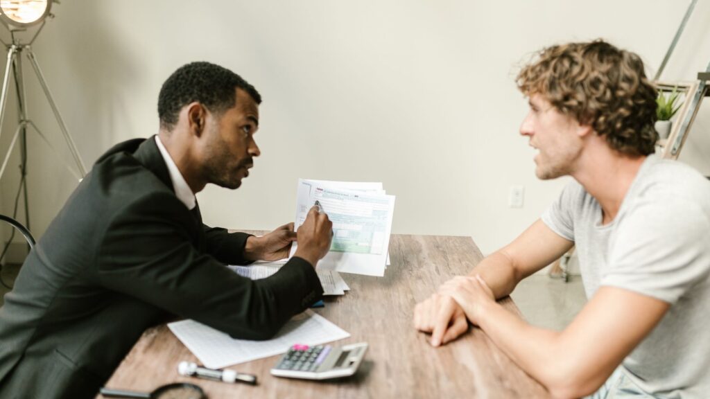 Business owner meeting with an accountant across a desk covered with financial paperwork and a calculator