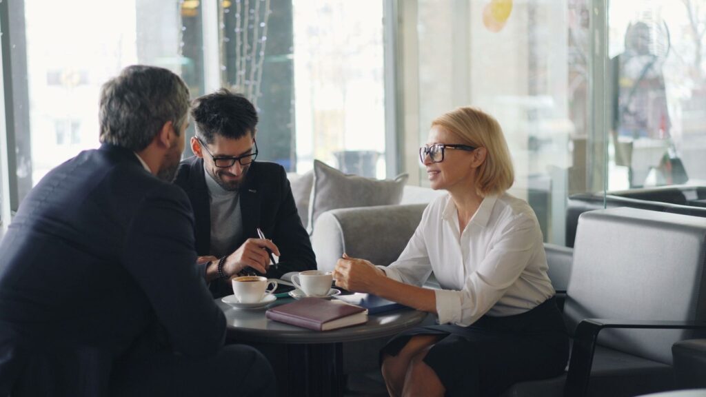 Business owner meeting with two advisors around a table in a bright lounge