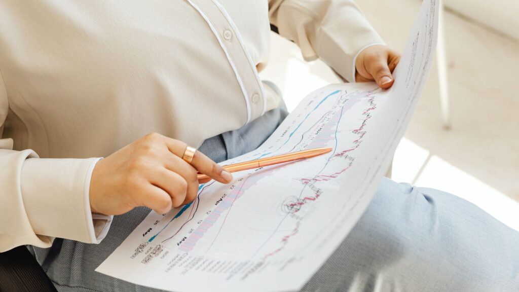 Business owner pointing a pencil at a printed line chart of financial results