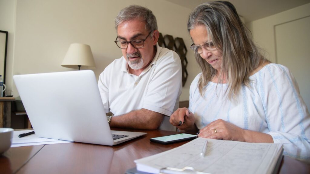 Couple reviewing retirement account paperwork together at a laptop at home