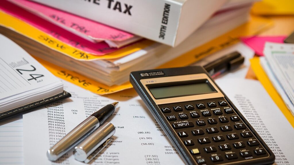 Income tax folders, forms, a pen and a calculator on a desk