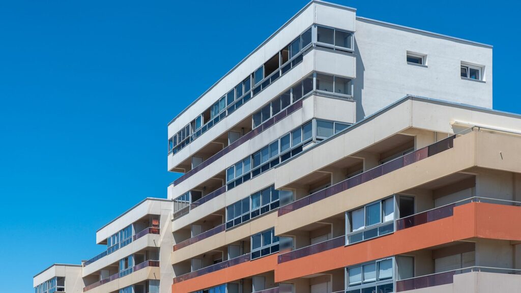 Modern multi-story apartment building with balconies against a clear blue sky