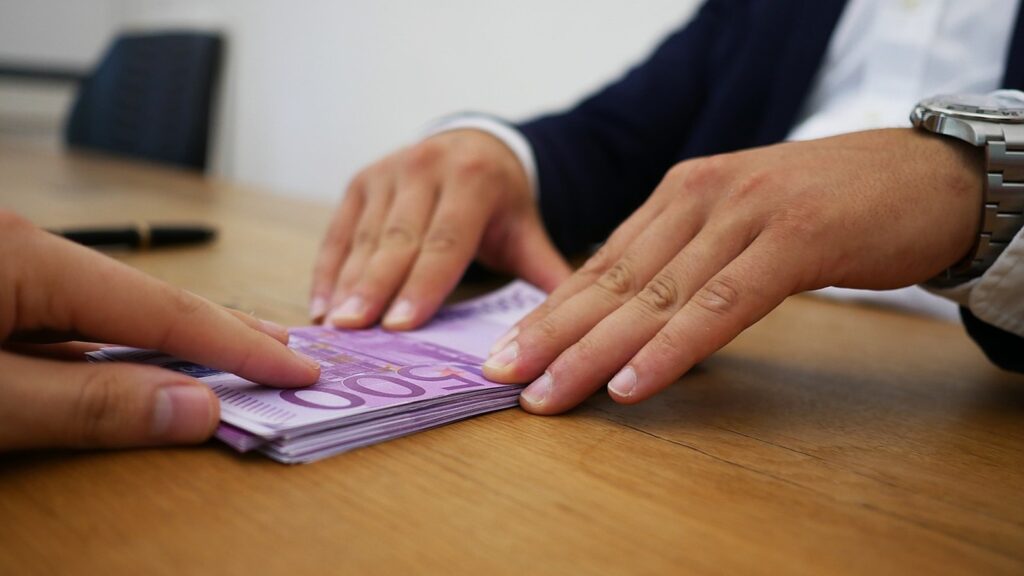 Two people passing cash across a desk